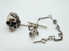 A silver watch chain made up of links in the form of bones and a skull to the end