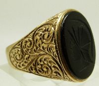 A 9ct gold ring set with an onyx intaglio with scrolling design to the shoulders, size U/V, 10.