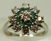 An 18ct white gold ring set with diamonds and emeralds in a large cluster, size M/N, 6.