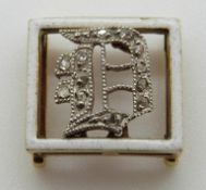Victorian buckle set with white enamel border and an inset diamond D,