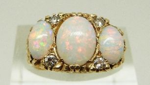 An 18ct gold ring set with three opals and paste, size L, 7.6g.