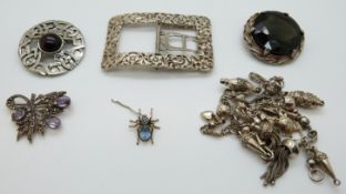 A white metal buckle (stamped), white metal fob chain with various charms, silver brooch,