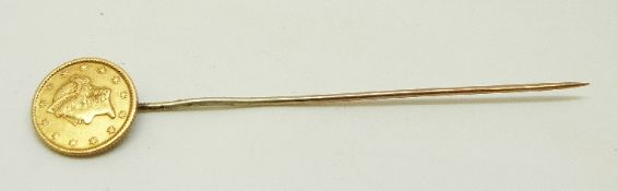A yellow metal stick pin set with a United States of America one dollar