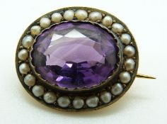 A yellow metal brooch set with an oval amethyst surrounded by seed pearls