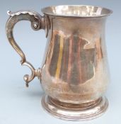 A George III hallmarked silver baluster shaped tankard, the scrolling handle with leaf decoration,
