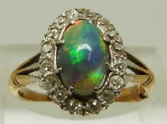 A Victorian 18ct gold ring set with a black opal cabochon surrounded by diamonds in a platinum