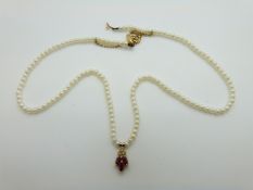 A single strand of pearls with an 18ct gold pendant set with rubies and diamonds