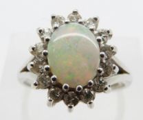 An 18ct white gold ring set with an oval opal cabochon surrounded by diamonds, size N, 3.