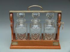 A three bottle mahogany tantalus with key, impressed PB and S, length 39cm,