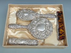 Cased modern hallmarked silver four piece embossed dressing table set including hand mirror
