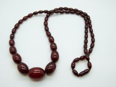 A cherry amber necklace of 61 graduated ovoid beads, the largest 29.2 x 21.