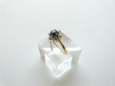 An 18ct gold ring set with a sapphire surrounded by diamonds, size M, 4.