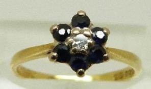 An 18ct gold ring set with a diamond surrounded by sapphires in a floral cluster, size K, 2.