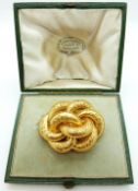 A Victorian pinchbeck knot brooch with filigree detail, verso a glass compartment,