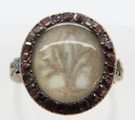 A Georgian mourning ring set with woven hair surrounded by pink paste,