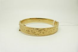 A 9ct gold bangle with engraved foliate design, 15.