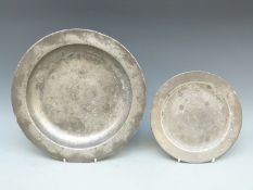 A pewter platter with touch marks and I I M to underside together with a smaller example with