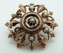 A rose gold brooch set with seed pearls in a pierced design,