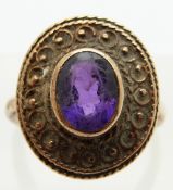 A 9ct gold ring set with an oval amethyst in filigree border, size N,