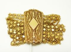 An Eastern yellow metal bracelet made up of eight strands of star links and a large filigree clasp,