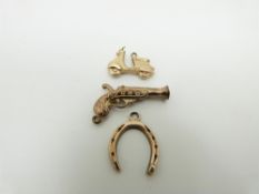 A 9ct gold charms in the form of Vespa, a 9ct gold horseshoe pendant and a 9ct gold gun charm, 3.