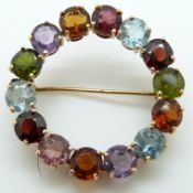 A yellow metal circular brooch set with garnets, peridot, citrine,