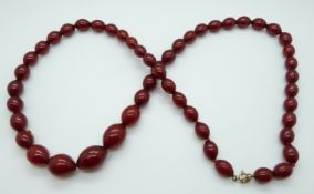 A cherry amber necklace of 51 graduated ovoid beads, the largest 25.