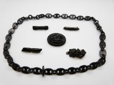 Five carved jet brooches and a vulcanite chain