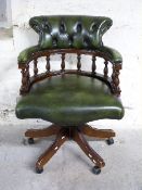 Captain's desk chair finished in olive green leather with button back and turned supports
