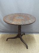 A carved oak circular tripod table,