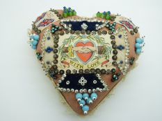A heart-shaped possibly WWI era sweetheart pin cushion with a collection of glass-topped pins