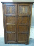 A panelled oak wardrobe with carved decoration,