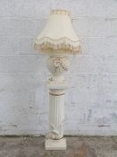 A faux carved stone plinth with lamp,