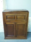 A mahogany desk or drinks cabinet with fall flap top and panelled cupboard below,