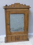 An early 20thC oak cupboard with mirrored door and drawer under, freestanding or hanging facility,