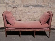 An upholstered hardwood day bed with drop ends raised on eight legs,
