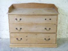 A pine chest of three graduated drawers with gallery back,