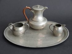 A pewter coffee pot, milk jug and sugar bowl on a tray,