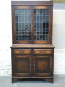 A leaded glass glazed oak bookcase over two drawers and two cupboards with adjustable dogs tooth