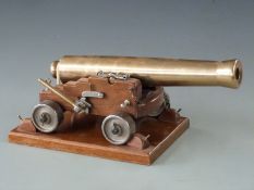 Signalling or display model cannon with 33cm graduated brass barrel raised on oak carriage and