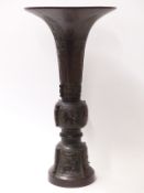 An 18th/19th Chinese bronze vase of gu form, the sides cast with bands of archaic style patterns,