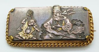 A 19thC yellow metal brooch set with a Japanese plaque depicting a man and devil, 5 x 2.