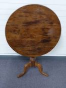 A 19thC oak circular tilt top table raised on a tripod base,