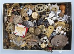 A tin containing a large quantity of military insignia, mostly cap badges,
