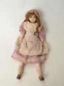 A wax headed doll with closed mouth, fixed blue eyes, long brown hair, wax limbs and soft body,