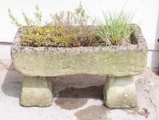 A weathered stone planter on two stone plinths length 92cm