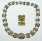 A silver filigree necklace made up of oval panels depicting dragons,