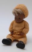 Sasha doll with brown lips, blue eyeshadow, brown hair, black shoes and knitted orange outfit,