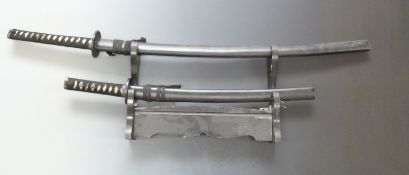 A pair of Japanese Samurai swords with faux shagreen bound handles and pierced and embossed tsuba,