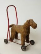 Blonde mohair straw filled child's push along dog on red metal frame, 38cm tall.
